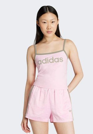 Rožinė medvilninė negabaritinė marškinėliai su pilkomis detalėmis ir "adidas" logotipu, derinami su atitinkamomis rožinėmis šortais, kurios turi pilkas šonines juostas ir kišenes.