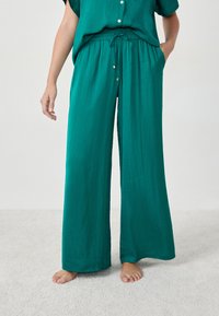 Luchtige teal broek met een elastische tailleband en koord. Gemaakt van lichtgewicht stof, met zijzakken en een gematteerde afwerking.