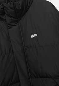 Doudoune noire dotée d'un col montant, d'un design matelassé et d'un logo blanc brodé. Tissu lisse avec une texture douce.