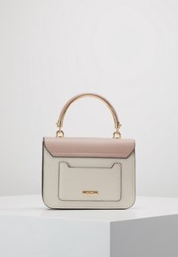Piccola borsa a mano con un design strutturato, con una patta superiore rosa chiaro e un corpo color crema, accentuata da finiture dorate e una tasca posteriore.
