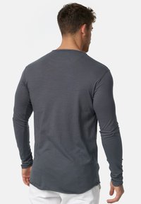 Camisa de manga larga en gris oscuro, con cuello redondeado, silueta ajustada, textura suave y dobladillo curvado.