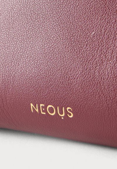 Υφή από δέρμα μπορντό με μικρά χρυσά γράμματα «NEOUS» που είναι ανάγλυφα κοντά στην κάτω άκρη.