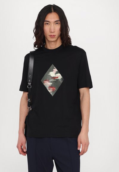 T-shirt negru cu mânecă scurtă, cu un grafic în formă de diamant în nuanțe de verde stins, alb și roșu, realizat dintr-un material moale.