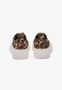 Leopard print slip-on shoes with a canvas upper, white rubber sole, and pulls at the heel for easy wear. Textured surface and round toe.
