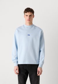 Felpa azzurro chiaro con collo rotondo e maniche lunghe, caratterizzata da un piccolo logo blu sul petto e polsini e fondo a costine.