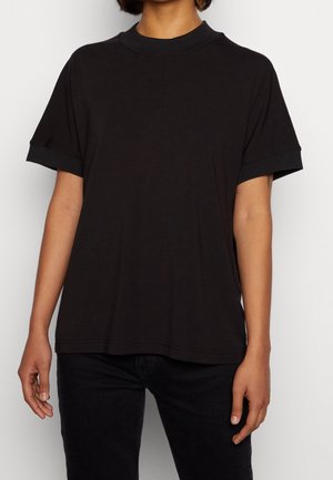 Schwarzes T-Shirt mit kurzen Ärmeln, einem gerippten Kragen und Bündchen, aus weichem Stoff gefertigt. Boxy-Design mit sichtbaren Nähdetails.