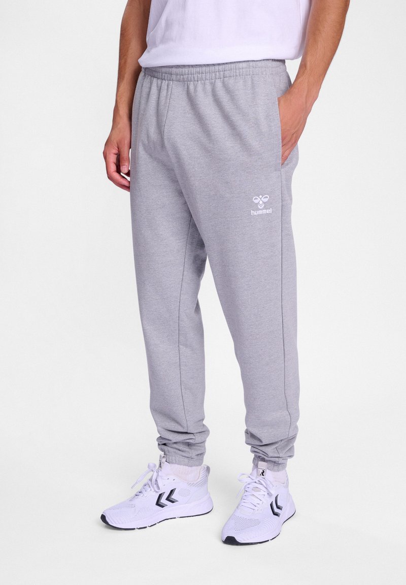 Graue Jogginghose mit elastischem Bund, gerippten Knöcheln und seitlichen Taschen. Mit einem kleinen weißen Logo auf der linken Seite.