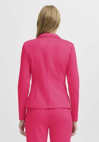 Op maat gemaakte roze blazer met een gestructureerde pasvorm, reverskraag en lange mouwen. Glad, textuurvol materiaal met een getailleerd silhouet en achternaad.