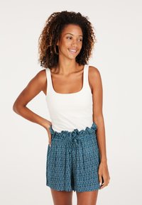 Hvid, ribbet tanktop med firkantet udskæring, parret med blå, mønstrede shorts med elastisk talje, der har en flæsekant og snøre.
