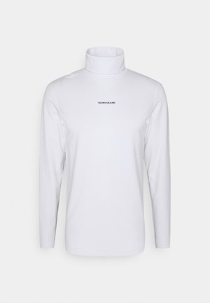 Hvid langærmet rullekravetrøje med "CALVIN KLEIN JEANS" logo centreret på brystet mod en ensfarvet baggrund.