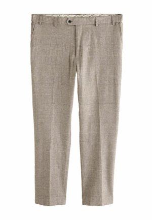 Gros plan sur un pantalon à carreaux beige avec un bouton noir, porté avec une chemise corail à manches longues rentrée.
