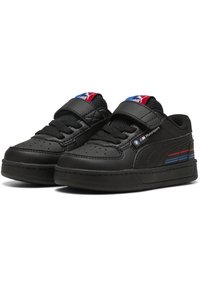 Baskets en cuir noir avec un bout perforé, des rayures contrastantes bleues et rouges sur le côté, et une sangle velcro sur les lacets.