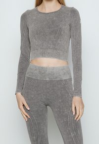 Grau farbliches Crop-Top und Leggings-Set aus weichem, strukturiertem Stoff. Verfügt über gerippte Bänder und gestickte Details entlang der Nähte.