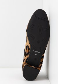Semelle d'une ballerine à imprimé léopard indiquant la taille 37, « Made in Spain », avec des motifs de chaussures de ballet embossés sur une semelle en caoutchouc noire.