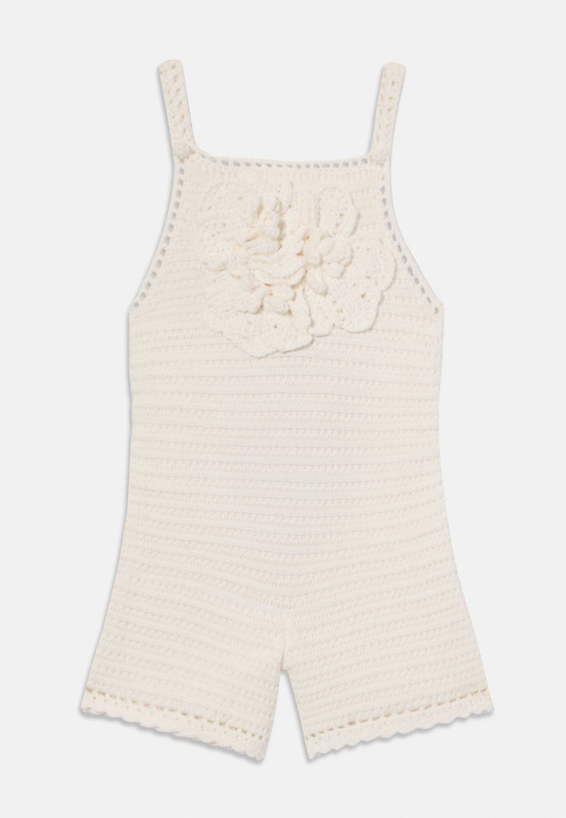 Crochet romper in cream, featuring narrow straps, a textured floral accent, and scalloped edges on shorts for added detail.