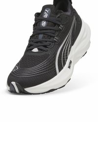 Bottines de sport noires présentant une tige en mesh texturé, un laçage de soutien, des lignes d'accent blanches et une semelle rembourrée et contrastante.