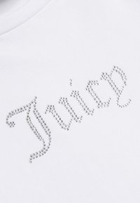 Valge puuvillane T-särk, millel on "Juice" disain, mis on valmistatud säravatest hõbedast rinestone'idest kõveras kirjas. Sile tekstuur ja ümmargune kaelus.