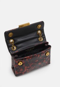 Svart och röd sköldpaddsmönstrad handväska med guldhardware, lås- stängning och fodrad insida med ett varumärkeslogotyp.