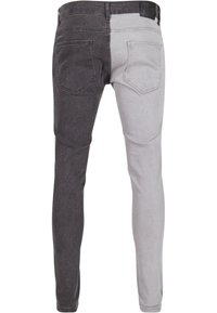 Deltone denimjeans med svart venstre side og lys grå høyre side. Fem lommer og standard midjebånd fullfører designet.