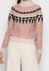 Rosa- und cremefarbener Pullover mit hohem Kragen, gemustert mit schwarz-weißen geometrischen Formen, aus weichem, strukturiertem Strickstoff.