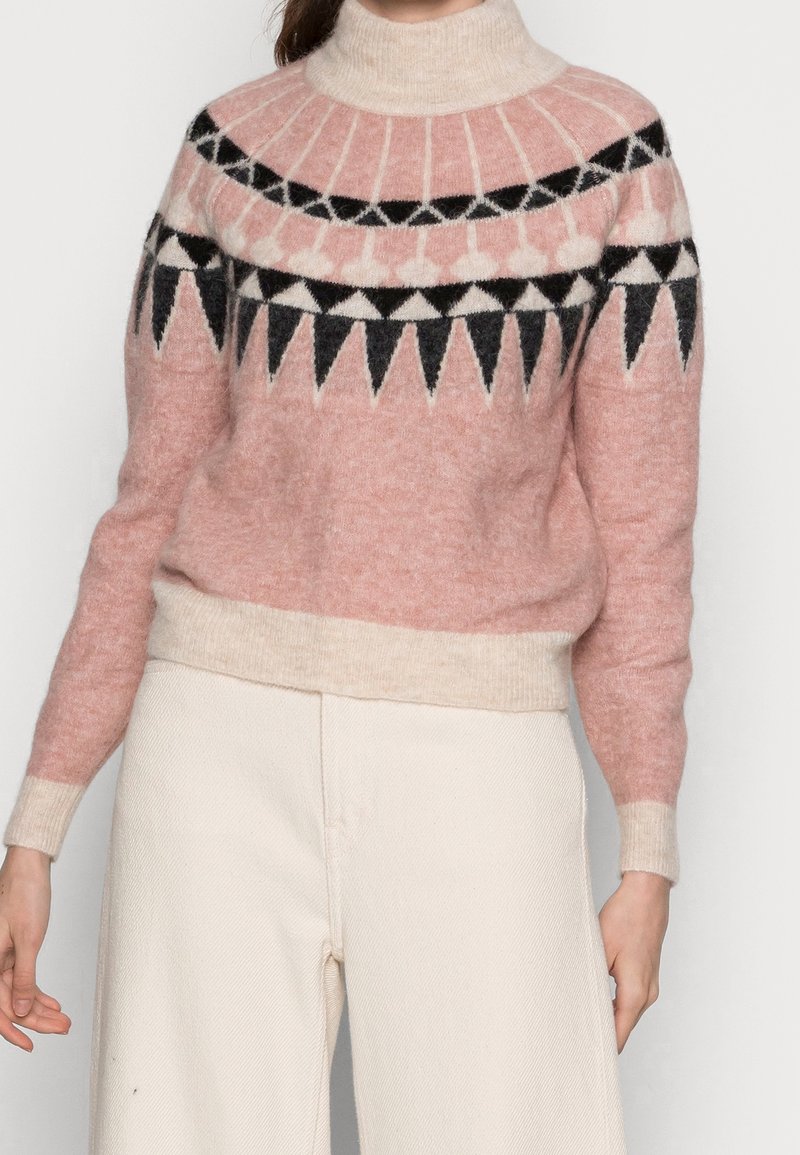 Rosa- und cremefarbener Pullover mit hohem Kragen, gemustert mit schwarz-weißen geometrischen Formen, aus weichem, strukturiertem Strickstoff.