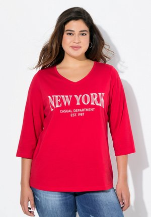 T-shirt en coton rouge avec un col en V, des manches trois-quarts et du texte blanc indiquant "DEPARTEMENT CASUAL DE NEW YORK FONDÉ EN 1987."