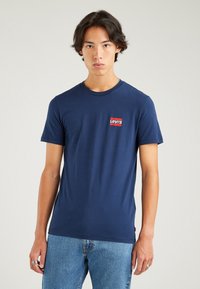 Navy blue cotton t-shirt with a round neck and short sleeves, featuring a small red and white Levi's logo on the left chest.