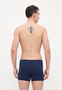 Marineblaue Boxershorts mit einer körpernahen Passform, hergestellt aus glattem Stoff, versehen mit einem mittelhohen Bund und minimaler Naht an den Kanten.