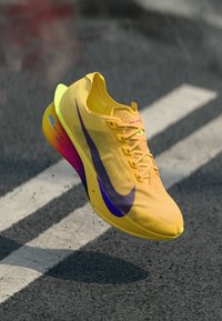 Nike-Laufschuh mit einem gelben, strukturierten Obermaterial, orangefarbenem Swoosh und einer Verlaufsohle, die von Pink zu Gelb übergeht.