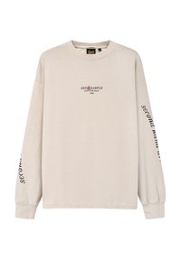 Beżowa długorękawowa bluza z bawełny, z czarnym i różowym logo tekstowym z przodu oraz napisem "second hand" na prawej rękawie.