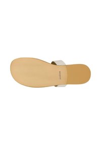 Semelle d’une sandale blanche à enfiler avec une semelle extérieure en caoutchouc beige plate et une large bride unique sur le pied.