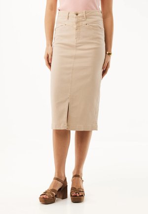 Beige, hoch taillierter Midirock mit vorderem Schlitz, kombiniert mit braunen Plateau-Sandalen und einem rosa ärmellosen Top, gezeigt von der Mitte des Oberkörpers bis zu den Füßen.