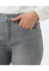 Šedé džíny z denimu s přední kapsou, vyznačující se viditelným stříbrným knoflíkem a slim fit střihem. Hladká textura s minimálními švy.