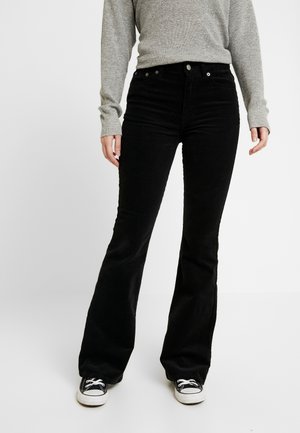 Black flared corduroy pants with a high waist, featuring five pockets, button closure, and subtle ribbed texture, paired with black sneakers.
