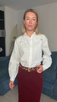 Fehér, gombos ing virágos hímzéssel a vállakon, bordó szoknyával és arany csattal ellátott, mintás barna övvel párosítva.