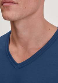 Navyblauwe V-hals t-shirt van gladde katoenen stof, met een schone halslijn en nette stiksels, en een nauwsluitende pasvorm rond de hals.