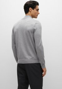 Grey knitted pullover with long sleeves, ribbed hem and cuffs, smooth texture, and a classic collar design. Suitable for casual wear.