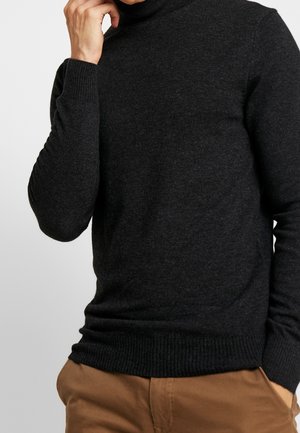 Suéter de cuello alto gris oscuro hecho de un tejido de punto suave, con puños y bajo acanalados. El diseño es ajustado y tiene una textura suave.