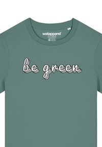 T-shirt en coton vert avec des manches courtes et un col rond, arborant la phrase "soyez vert" en texte ondulé blanc contouré de noir.