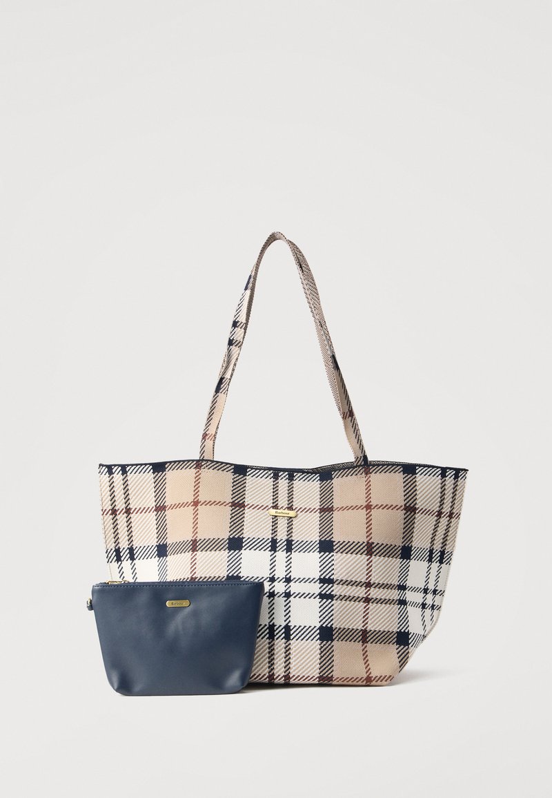 Τσάντα tote με καρό σχέδιο σε μπεζ, ναυτικό μπλε και λευκό, συνοδευόμενη από μια τσαντούλα με φερμουάρ σε ναυτικό μπλε, και οι δύο με χρυσές πλακέτες με το όνομα της μάρκας.