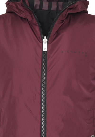 Giacca zip-up bordeaux con cappuccio, dotata di zip nera, polsi elasticizzati e un piccolo logo stampato sul petto in nero.