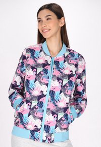 Bloemen bomberjack met een marineblauwe achtergrond, kleurrijke roze flamingo- en tropische bladerenprints, met een lichtblauwe geribbelde kraag en manchetten.