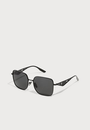 Lunettes de soleil noires avec des verres carrés et une fine monture en métal noir à motifs. Les branches présentent un design texturé pour une meilleure adhérence.