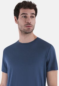 Mørkeblå t-skjorte med korte ermer laget av mykt stoff. Har rund halslinning og en glatt tekstur uten mønstre eller detaljer.