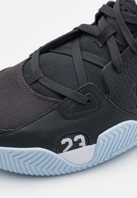 Černé sneakers s texturovaným svrškem, který kombinuje síťovinu a kůži. Mezi prvky patří bílý nápis "23" a světle modrá vzorovaná podrážka.