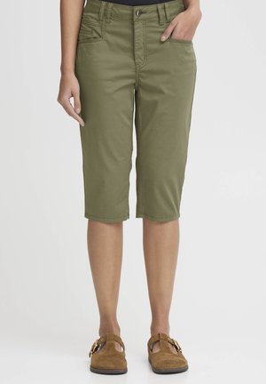 Olivgrüne Bermuda-Shorts mit Reißverschluss und Knopfverschluss, fünf Taschen und geradem Saum, kombiniert mit braunen Wildleder-Slippern.