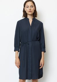 Abito blu navy realizzato in tessuto liscio, con colletto alla cinese, maniche tre quarti e vita con fiocco per una vestibilità regolabile.