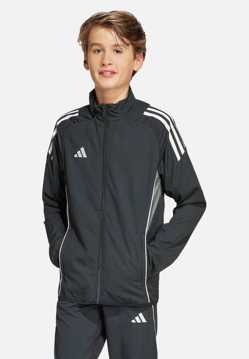 Schwarze Sportjacke mit weißen Streifen, Reißverschluss vorne, Stehkragen und Seitentaschen; mit Adidas-Logo auf der Brust und an den Hosen.