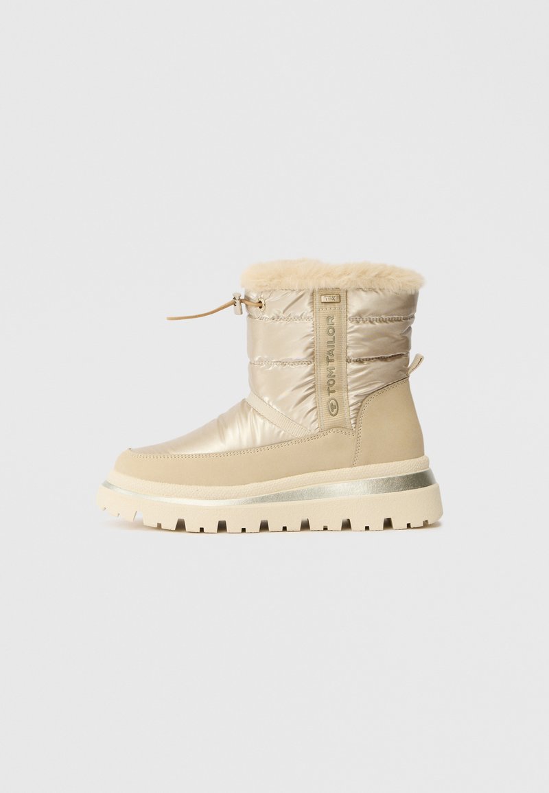 Beige winter boot with shiny textile upper, faux fur collar, and textured rubber sole. Features a branded strap and adjustable drawstring.