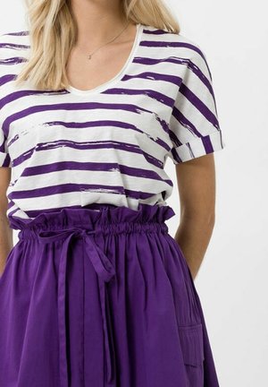 T-shirt rayé aux lignes horizontales violettes et blanches ; associé à une jupe violette taille haute avec cordon de serrage à la taille et poches.